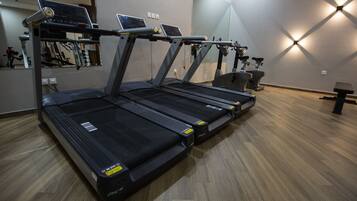 A gym with multiple treadmills, exercise bikes, and a mirrored wall.