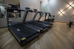 A gym with multiple treadmills, exercise bikes, and a mirrored wall.