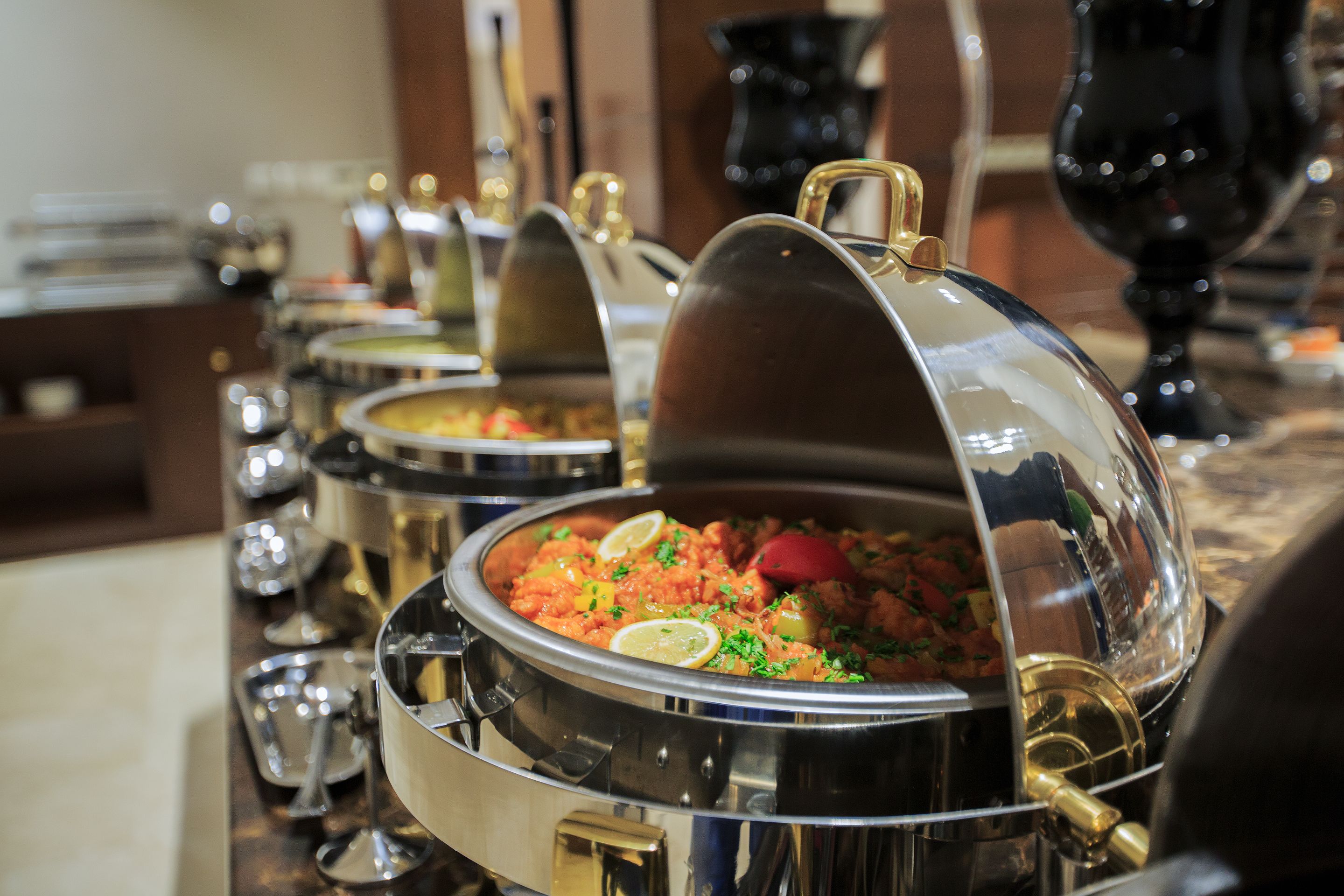 Una mesa de buffet con varios recipientes cubiertos con tapas abovedadas.