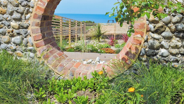 Une arche circulaire en briques offrant une vue sur la mer.