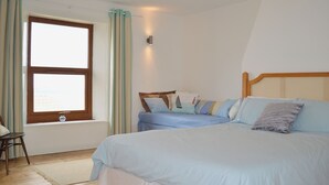 Une chambre à coucher comprenant un lit, une chaise, une fenêtre et un luminaire fixé au mur.