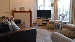 A living room with a sofa, television, and a fireplace.