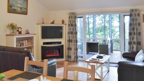 A living room with a fireplace, a television, and a dining area. - 2 bedroom accommodation in Clatworthy, near Williton (Clatworthy, near Williton)
