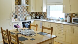 A kitchen with a dining area, equipped with a stove, sink, and cabinets. - 2 bedroom accommodation in Clatworthy, near Williton (Clatworthy, near Williton)