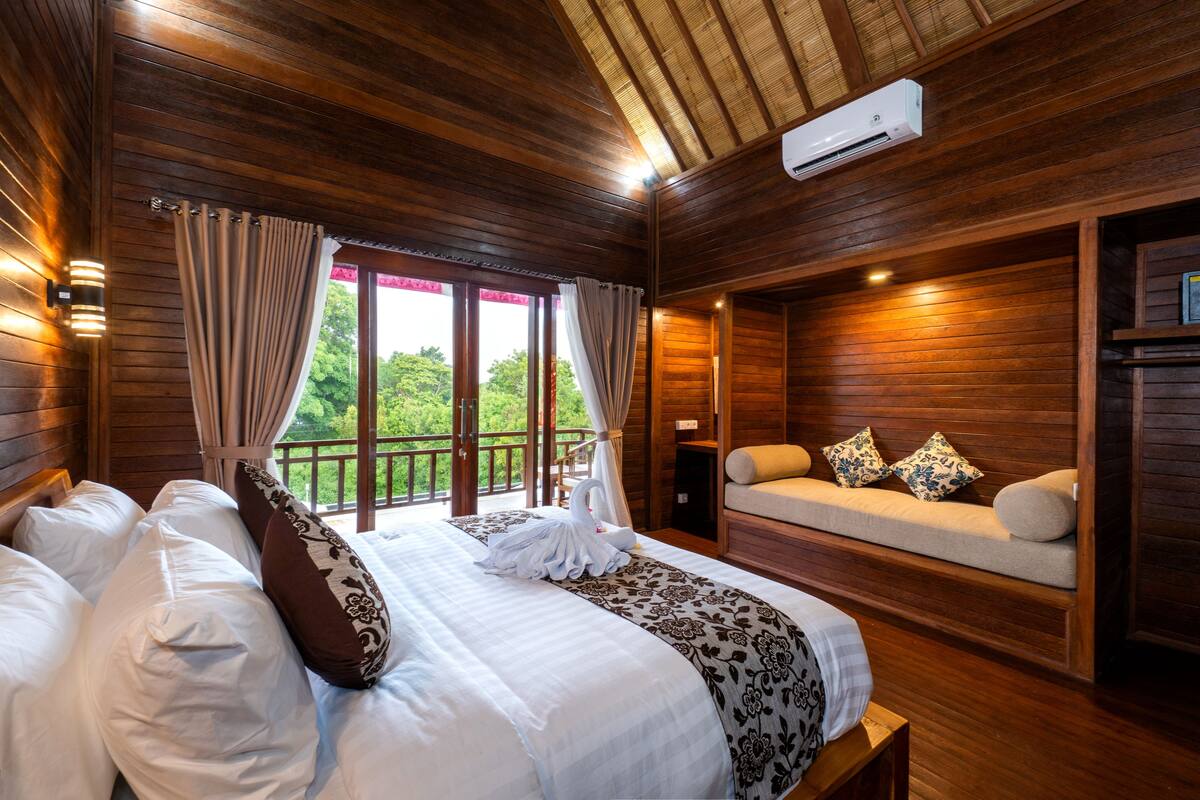 Un dormitorio de cabaña de madera con una cama, un sofá y una ventana con cortinas.