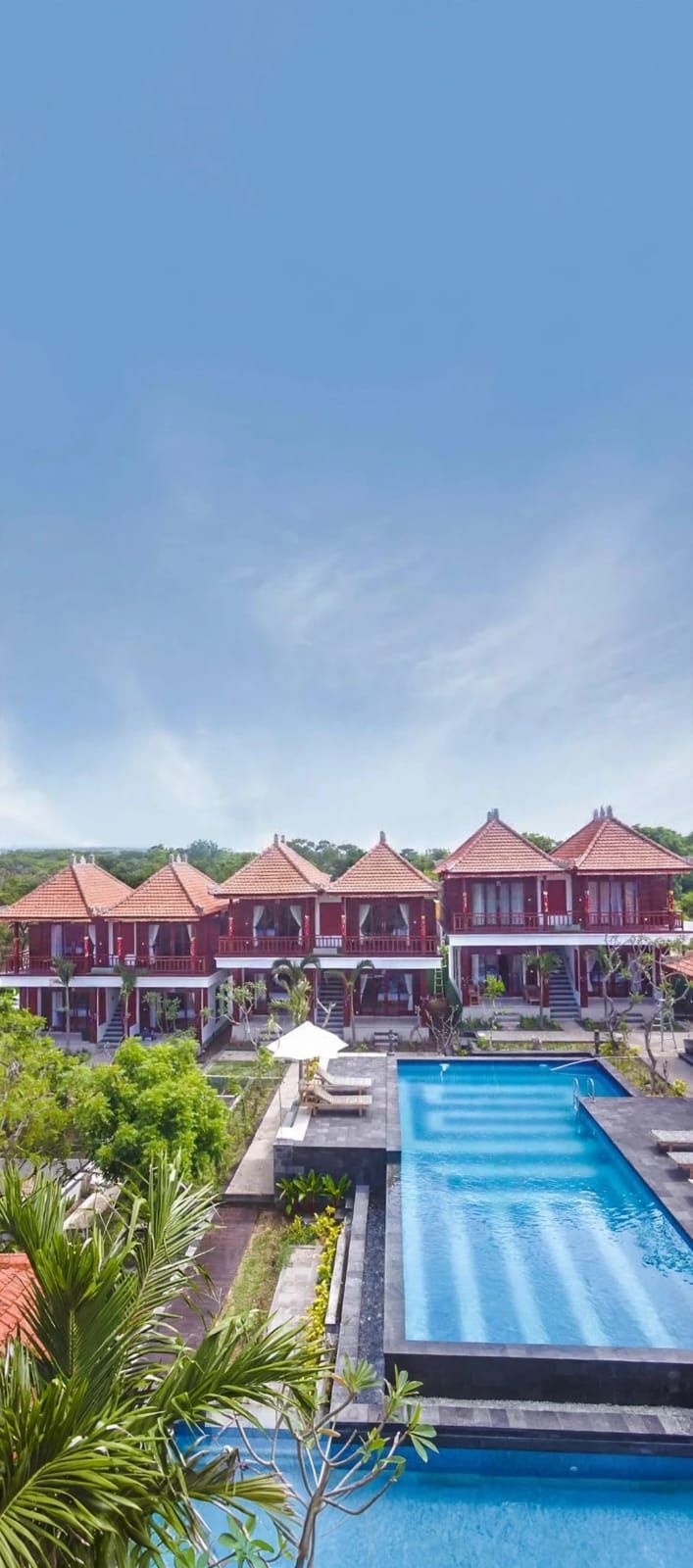 A resort with multiple red-roofed buildings, a swimming pool, and lush greenery.