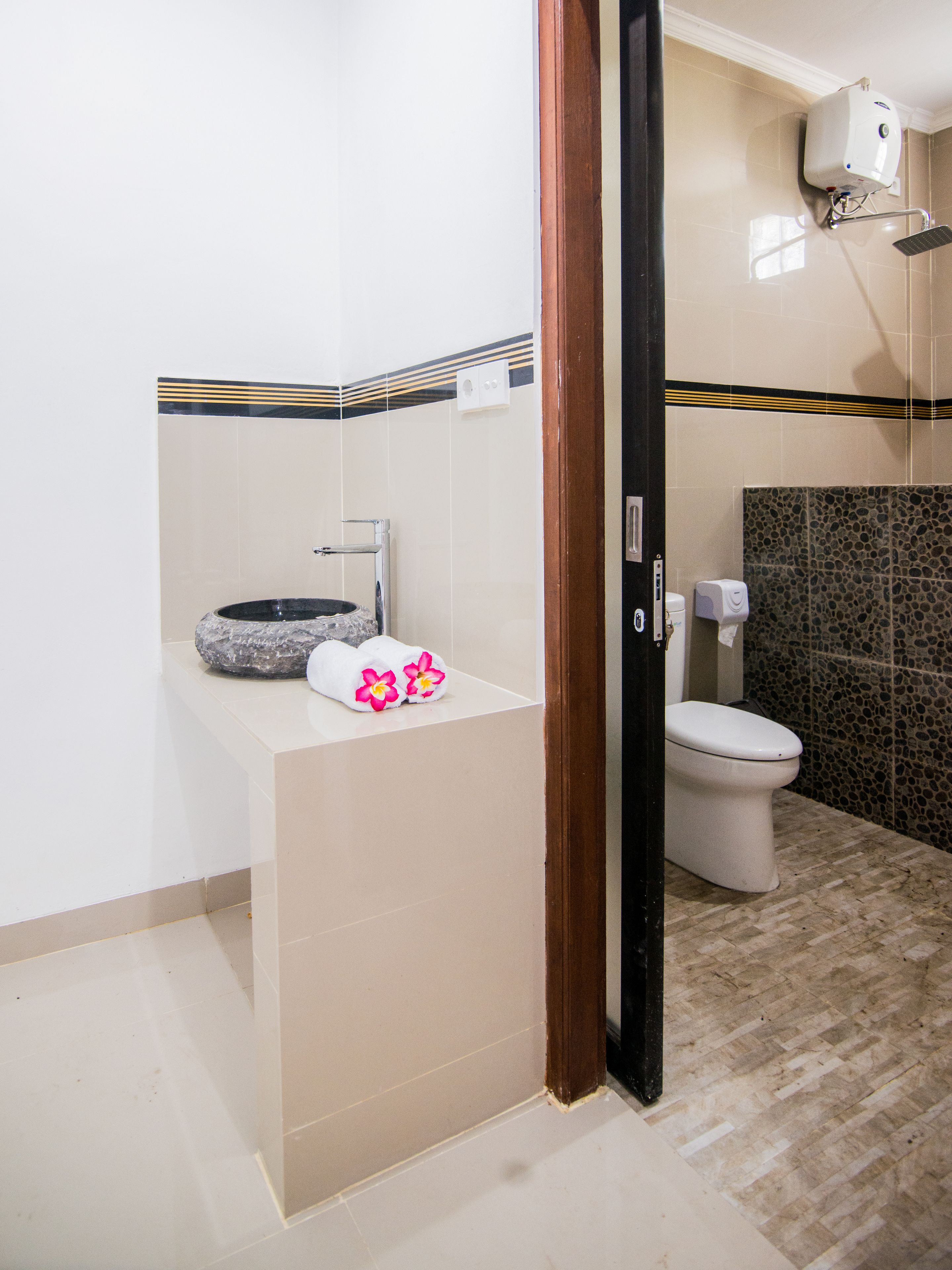 Une salle de bain avec un lavabo en pierre, des toilettes et un sèche-mains.