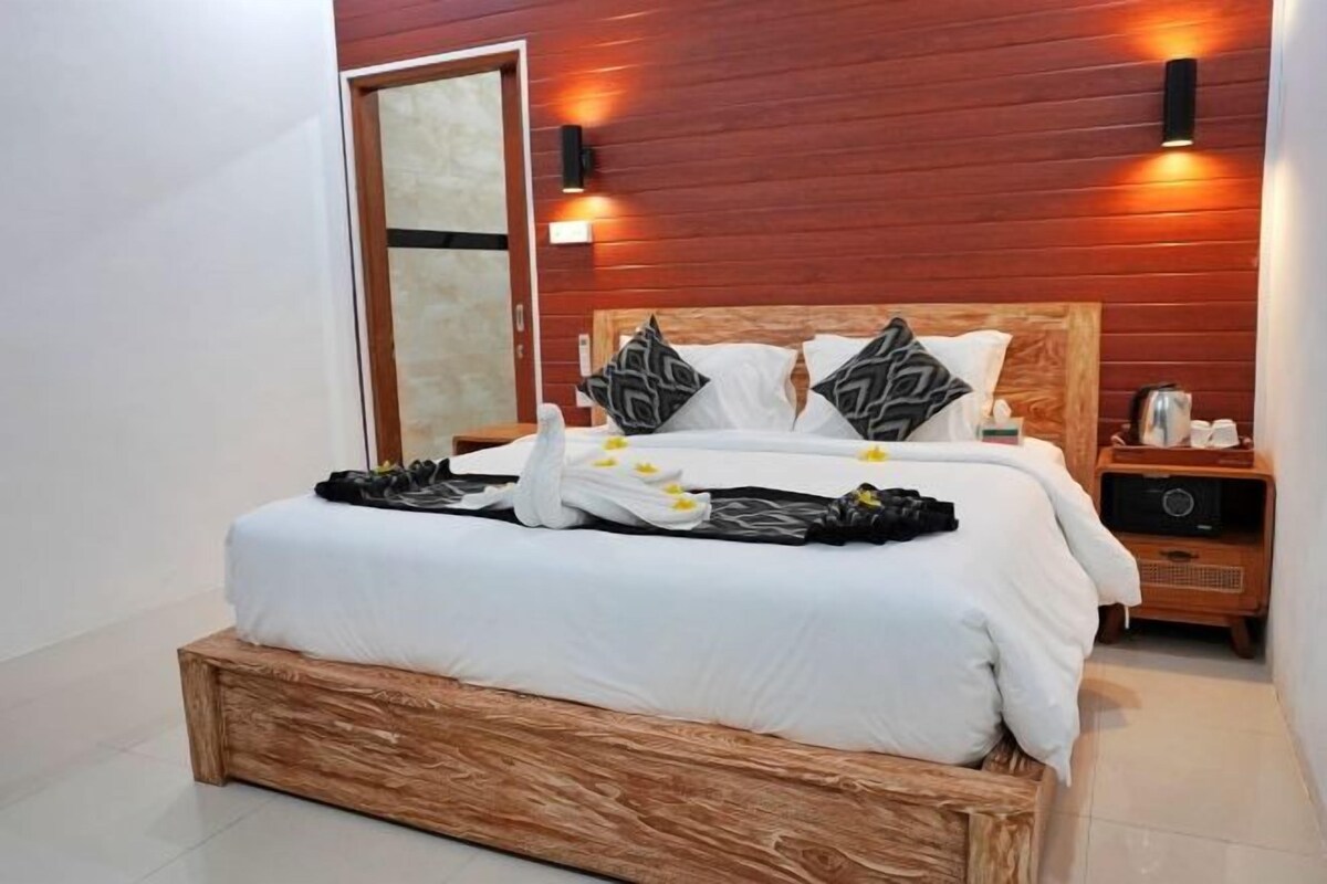 Una cama bien hecha con cabecera de madera, ropa de cama blanca y almohadas decorativas.