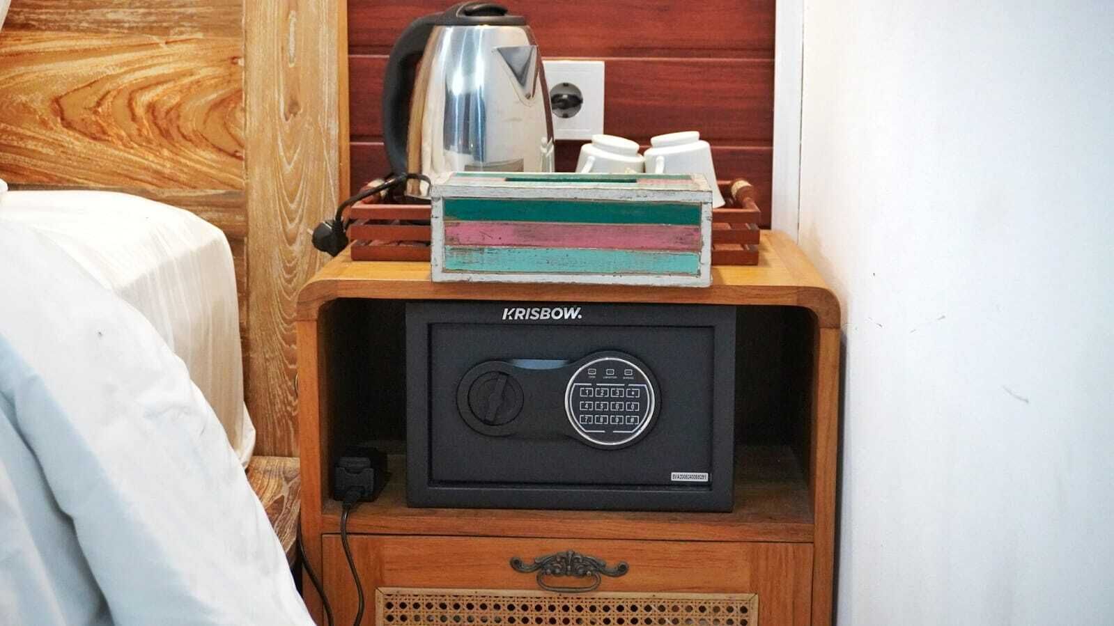 Une petite pièce avec un meuble en bois contenant un appareil noir portant l’inscription « KRISBOW ». Une bouilloire et un récipient blanc sont posés sur le dessus du meuble.