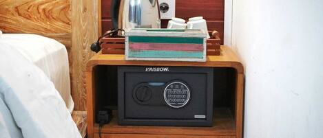 Una habitación compacta con un mueble de madera que contiene un electrodoméstico negro etiquetado 'KRISBOW'. Una tetera y un recipiente blanco están encima del mueble.