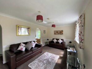 A living room with a brown leather sofa, a white shag rug, and a red pendant light.