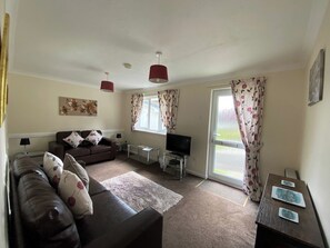 A living room with a sofa, TV, and a dining table with placemats.