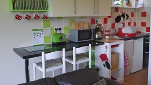 Eine kompakte Küche mit Essbereich, ausgestattet mit einer Mikrowelle, einem Toaster und einem kleinen Spülbecken.