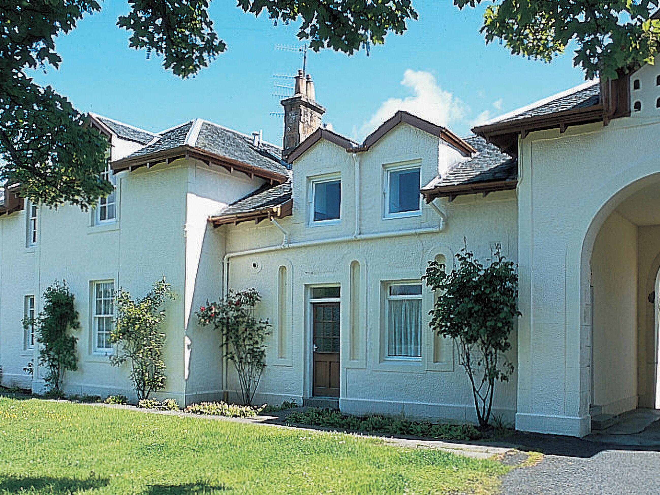 A large, two-story house with a symmetrical facade, multiple windows, and a central entrance.