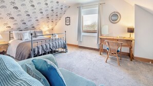 A bedroom with a bed, a desk, a chair, a mirror, and a window.