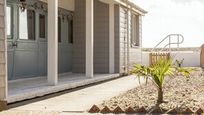 Ein Haus mit Veranda, einer Tür und einem kleinen Garten mit Pflanzen und Zierelementen.