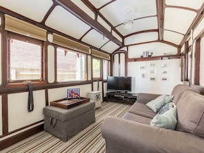 A train carriage interior with a sofa, television, and a chessboard.