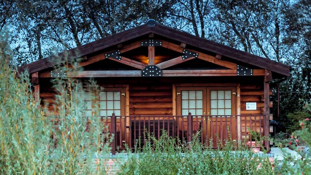 Eine Holzhütte mit Veranda, umgeben von Bäumen.