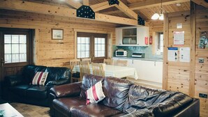 Ein gemütliches Blockhaus-Interieur mit Ledersofa, Holzwänden, Essbereich und Küche.