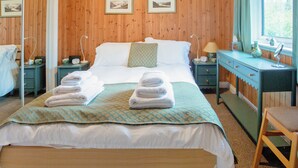 Une chambre aux murs lambrés, avec un lit, deux tables de chevet, une commode et une chaise.