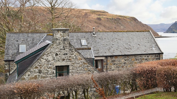 A stone house with a sloped roof, a chimney, and a window. - 2 bedroom accommodation in Portree (Portree)