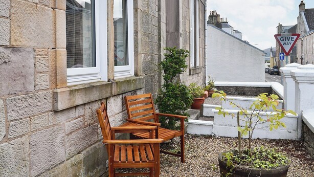 A stone building with a wooden bench and potted plants. - 1 bedroom accommodation in Millport, Isle of Cumbrae (Millport, Isle of Cumbrae)