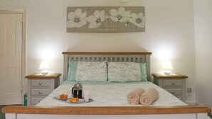 Een slaapkamer met een bed, twee nachtkastjes, een wanddecoratie en een deur.