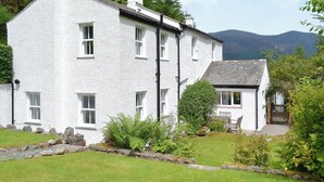 A white building with multiple windows, a stone pathway, and a small garden area.