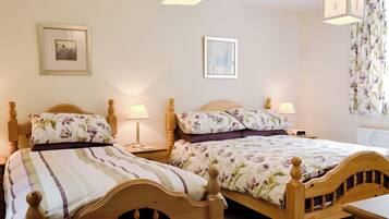 A bedroom with two wooden beds, each with floral bedding and bedside lamps.