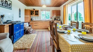 A cozy kitchen with wooden cabinets, a blue stove, and a dining area with a table set for two. - 3 bedroom accommodation in Arkleby, near Cockermouth (Arkleby, near Cockermouth)