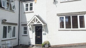 A white building with a black door, a small porch, and a satellite dish. - 3 bedroom accommodation in Windermere (Windermere)