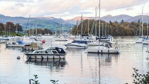 A marina with multiple boats docked, surrounded by hills and trees. - 3 bedroom accommodation in Windermere (Windermere)