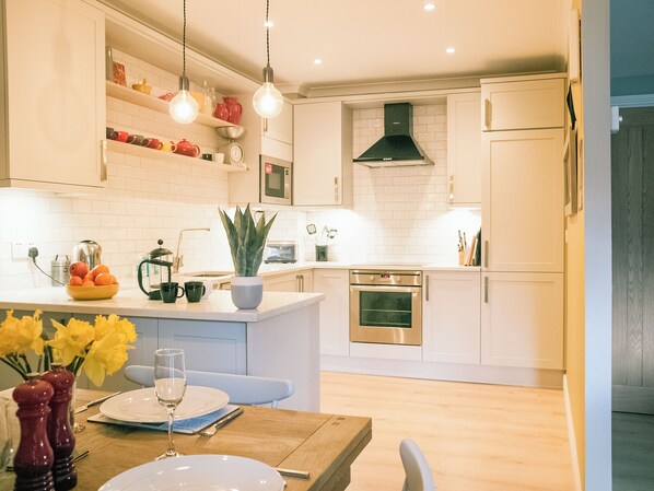 A modern kitchen with white cabinets, a central island, a microwave, oven, and a sink. - 3 bedroom accommodation in Windermere (Windermere)