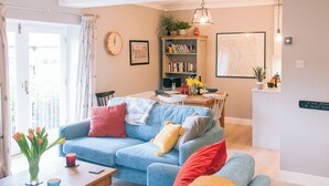A living room with a blue sofa, a coffee table, and a bookshelf. - 3 bedroom accommodation in Windermere (Windermere)