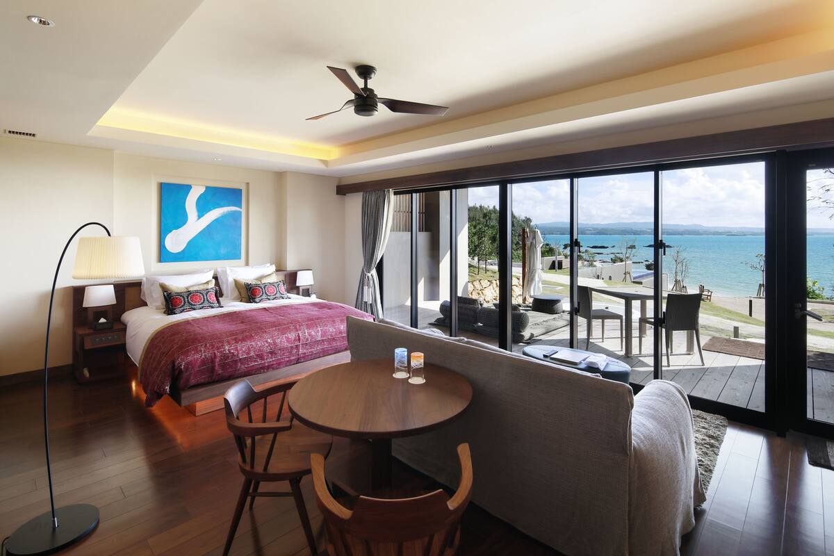 Een hotelkamer met een bed, een ronde tafel en uitzicht op zee.