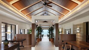 A spacious lobby with a high ceiling, wooden beams, and a central seating area with tables and chairs. - The Hiramatsu Hotels & Resorts Ginoza (Ginoza)