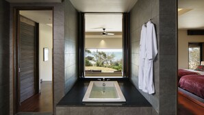 A modern bathroom with a large bathtub, a view of the ocean, and a ceiling fan. - The Hiramatsu Hotels & Resorts Ginoza (Ginoza)