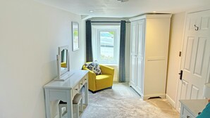 A bedroom with a bed, a desk, a chair, a wardrobe, and a window with curtains. - A traditional Lakeland cottage situated in the heart of Portinscale village. (Portinscale, near Keswick)