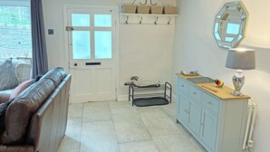 A room with a door, a coat rack, a mirror, a lamp, a cabinet, and a window. - A traditional Lakeland cottage situated in the heart of Portinscale village. (Portinscale, near Keswick)