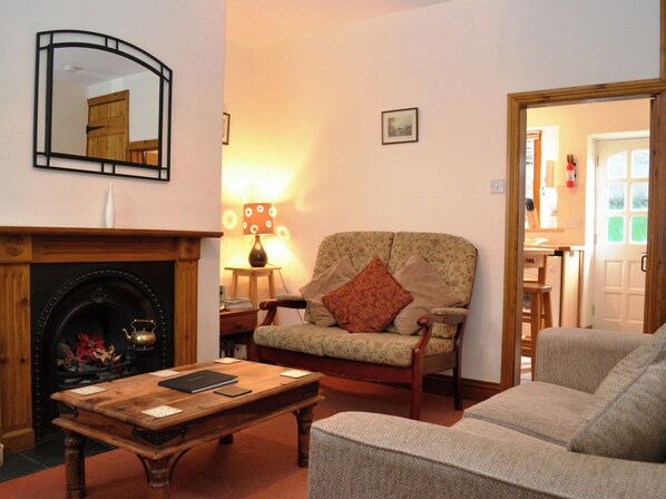 A cozy living room with a fireplace, a sofa, a coffee table, and a lamp.