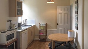 A compact kitchen with a microwave, toaster, sink, and a small dining table. - 2 bedroom accommodation in Staindrop, near Barnard Castle (Staindrop, near Barnard Castle)