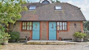 Une maison traditionnelle en briques, dotée de deux portes, d’un toit en pente et d’un petit porche.