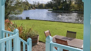 A view of a river with ducks, a grassy area, and a wooden table with chairs. - 3 bedroom accommodation in Hoveton, near Wroxham, Norwich (Hoveton, near Wroxham, Norwich)