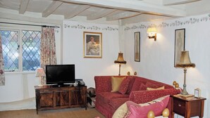 Ein gemütliches Wohnzimmer mit einem roten Sofa, einem Fernseher und zwei Lampen.