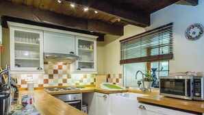 A kitchen with white cabinets, a microwave, a sink, and a window with blinds.