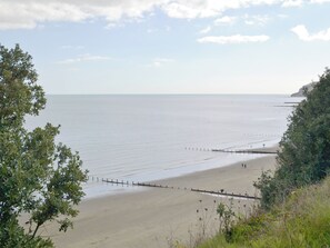 A beach with a wooden fence, calm water, and a clear sky.
