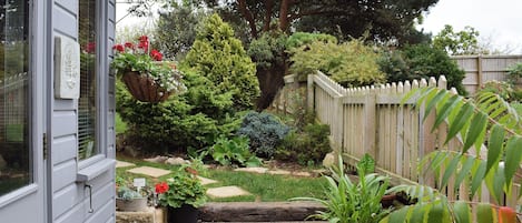 Um jardim com cerca de madeira, diversas plantas e uma placa de boas-vindas.