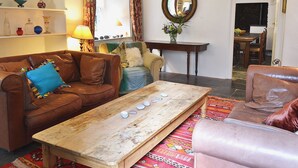 Een gezellige woonkamer met een bruine leren bank, een houten bijzettafeltje en een kamerkleed met dessin.