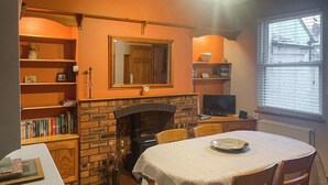 Une pièce chaleureuse avec une cheminée, des étagères à livres, une table à manger et un téléviseur.