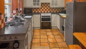Une cuisine avec des meubles blancs, une cuisinière, un évier et un réfrigérateur.
